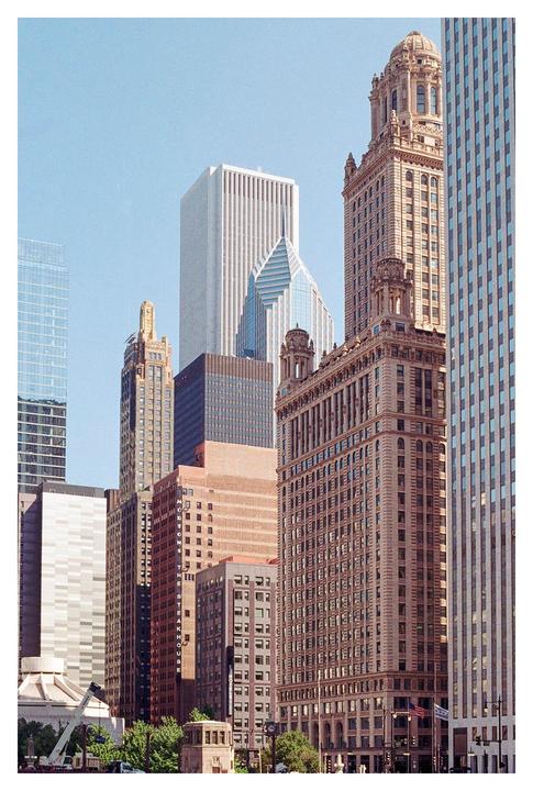 A cluster of diverse skyscrapers and buildings rise into a clear sky.