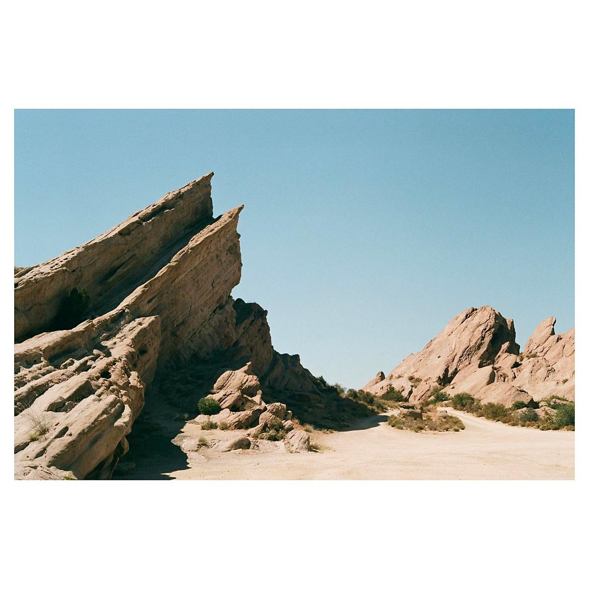 Jagged rock formations rise from a desert landscape under a clear sky.