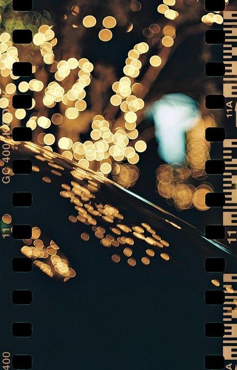 A dark image features numerous golden bokeh lights, with a few blue lights visible in the background.
