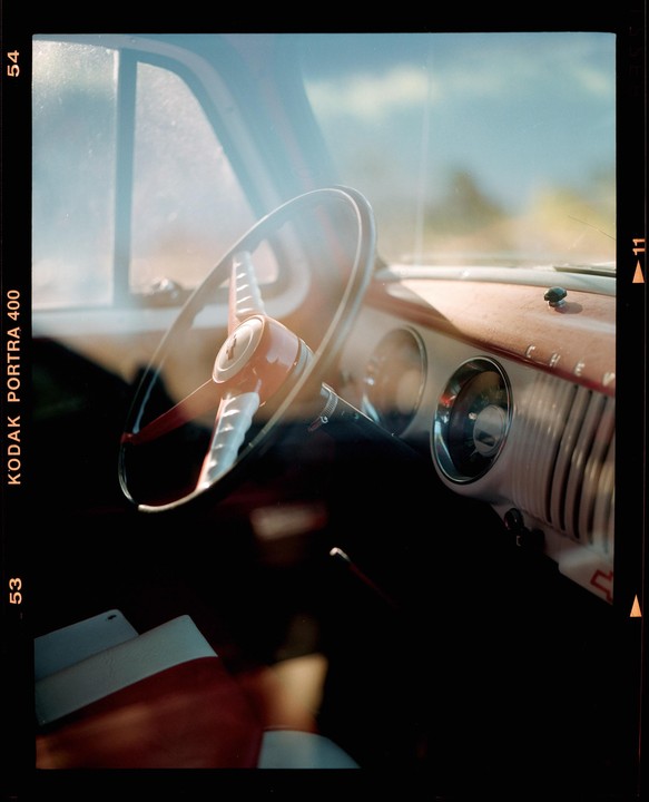 The interior of a vintage car is visible through the windshield, showing the steering wheel and dashboard.