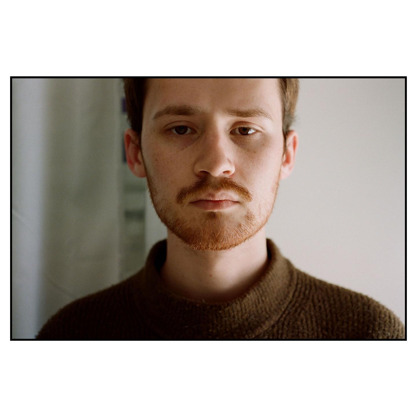 A man with a beard and mustache looks directly at the viewer.