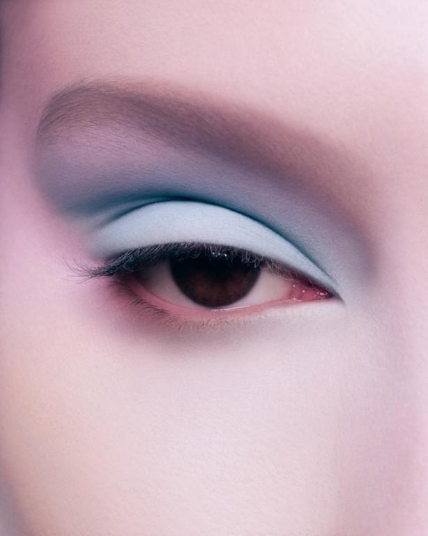 A person's eye is visible with blue eyeshadow and a dark iris.