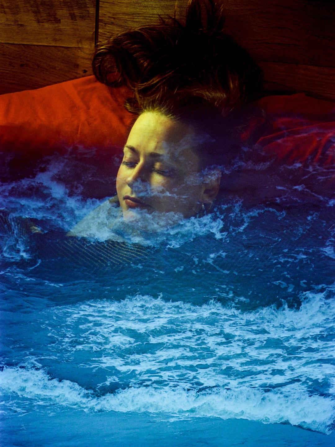 A woman with closed eyes is shown in a double exposure with ocean waves.