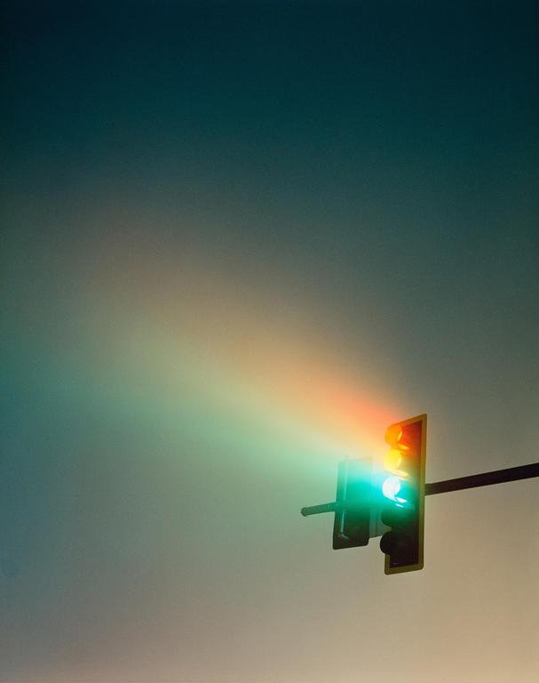 A traffic light with a green light illuminated shines through a hazy atmosphere.