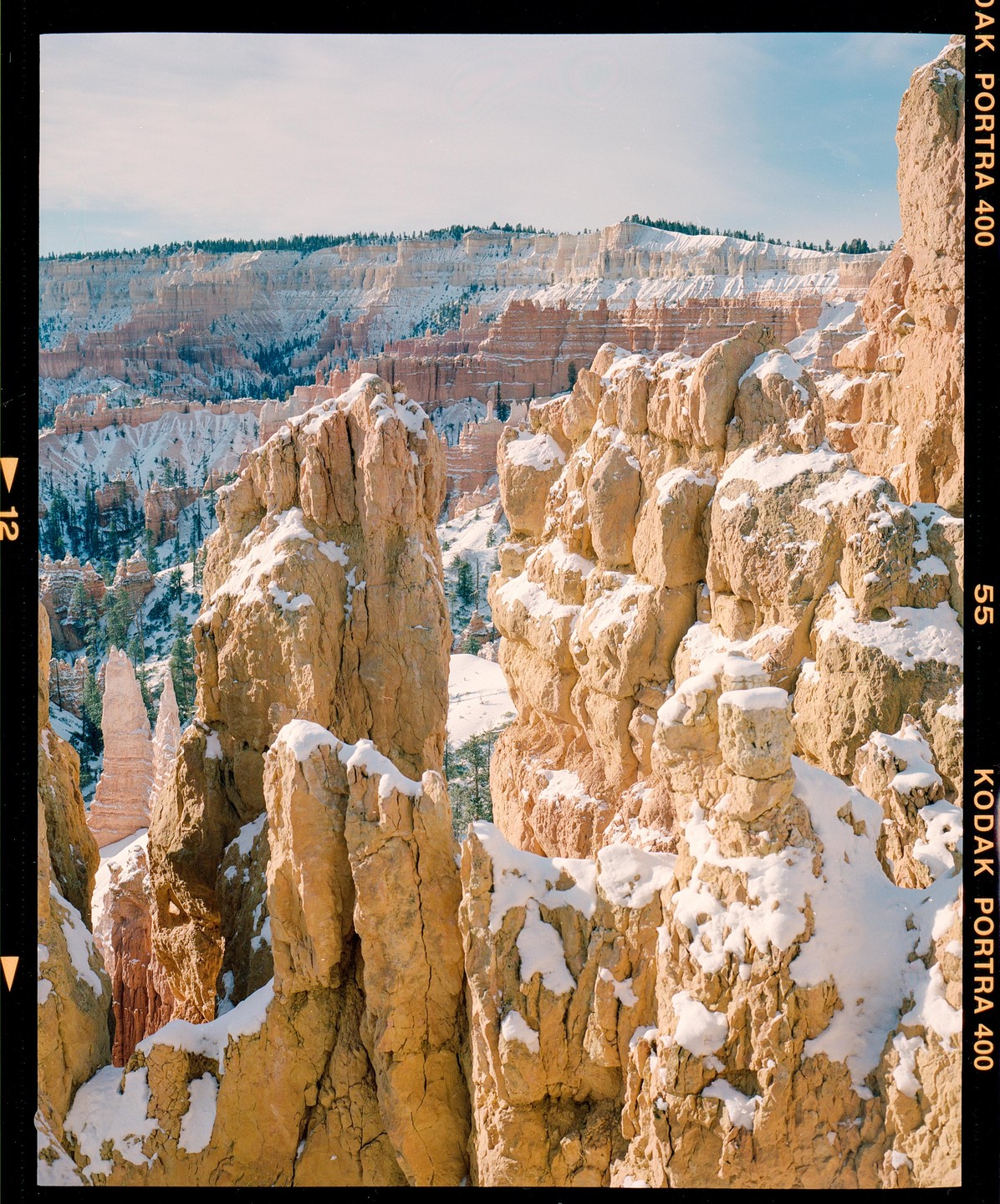 Snow covers the tops of orange rock formations in Bryce Canyon.