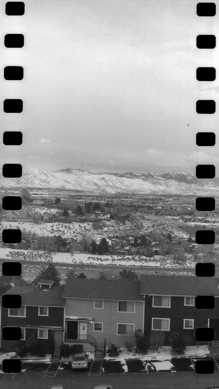 A snowy landscape with houses in the foreground and mountains in the background is visible through a film strip.