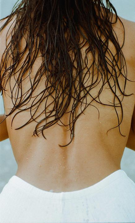 The back of a person with wet hair and water droplets on the skin is visible.