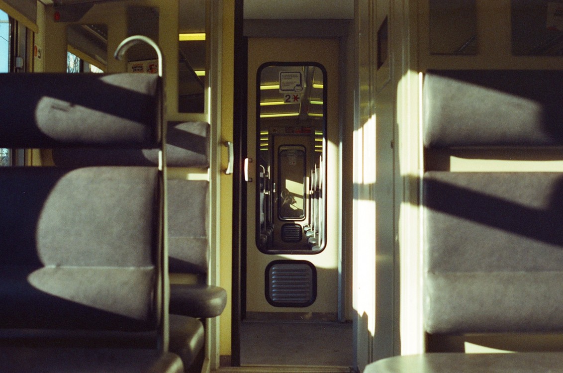 Sunlight streams into an empty train car, illuminating the seats and creating strong shadows.
