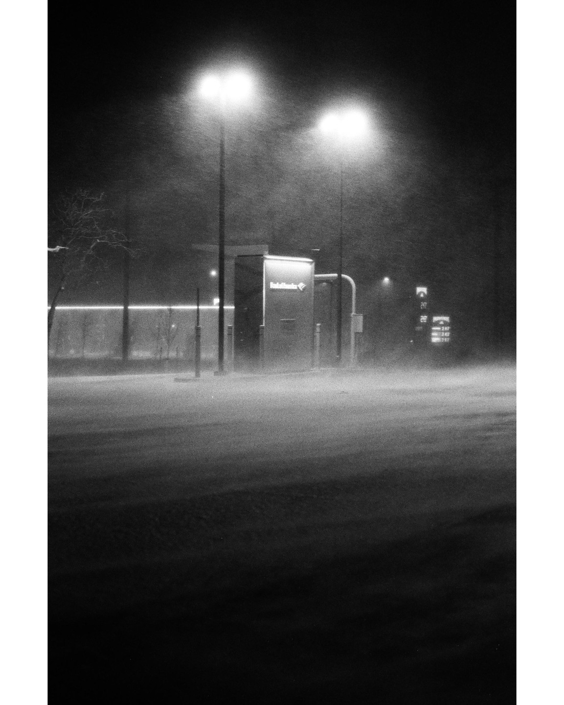 A gas station is illuminated by streetlights during a snowy night.