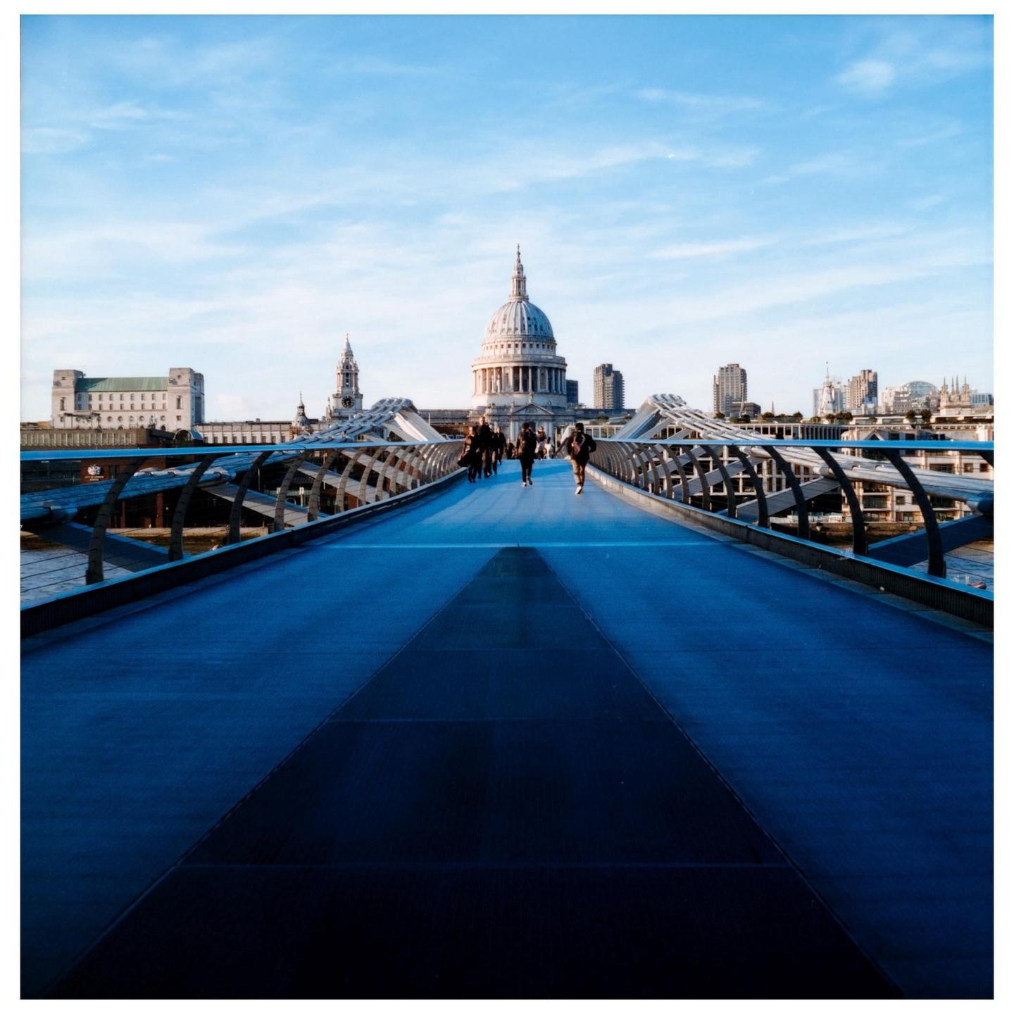 People walk across the Millennium Bridge towards St Paul's Cathedral in London.