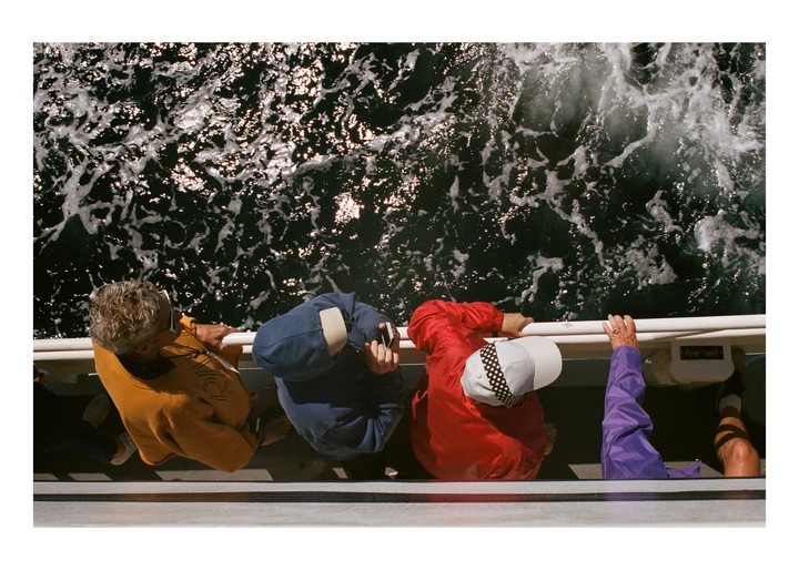 Three people are looking down at the foamy water from a boat.