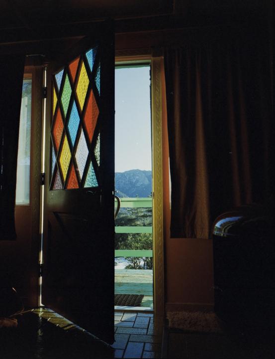 A stained glass door opens to a mountain landscape.