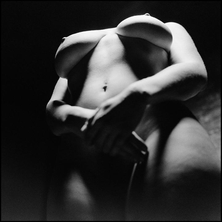 A woman's torso is visible from a low angle, with her hands covering her lower body.
