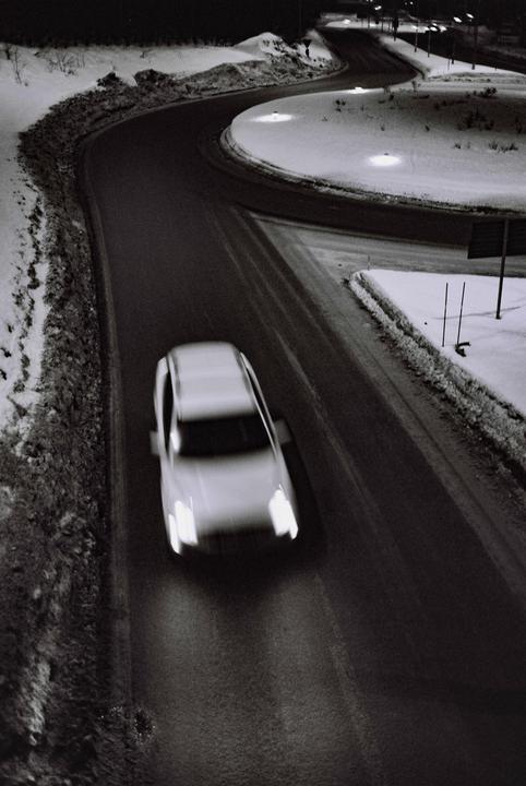 A car drives along a winding road covered in snow at night.