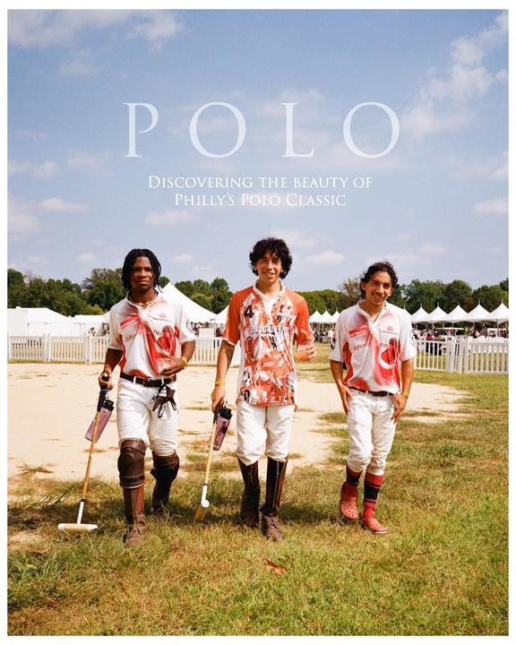 Three men in polo attire stand on a grassy field with polo mallets, with a white fence and tents in the background.