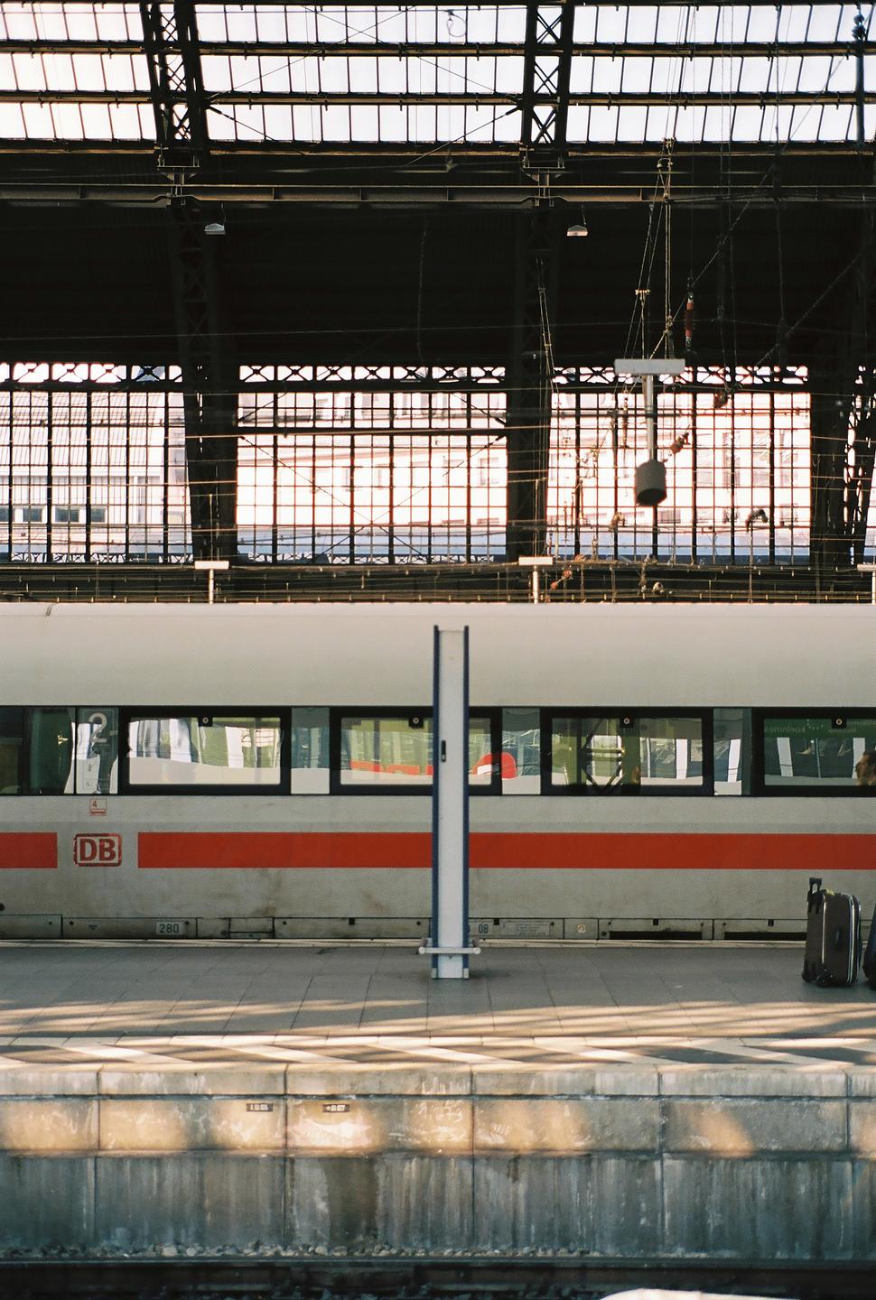 A train is stopped at a station platform under a large glass and metal roof.