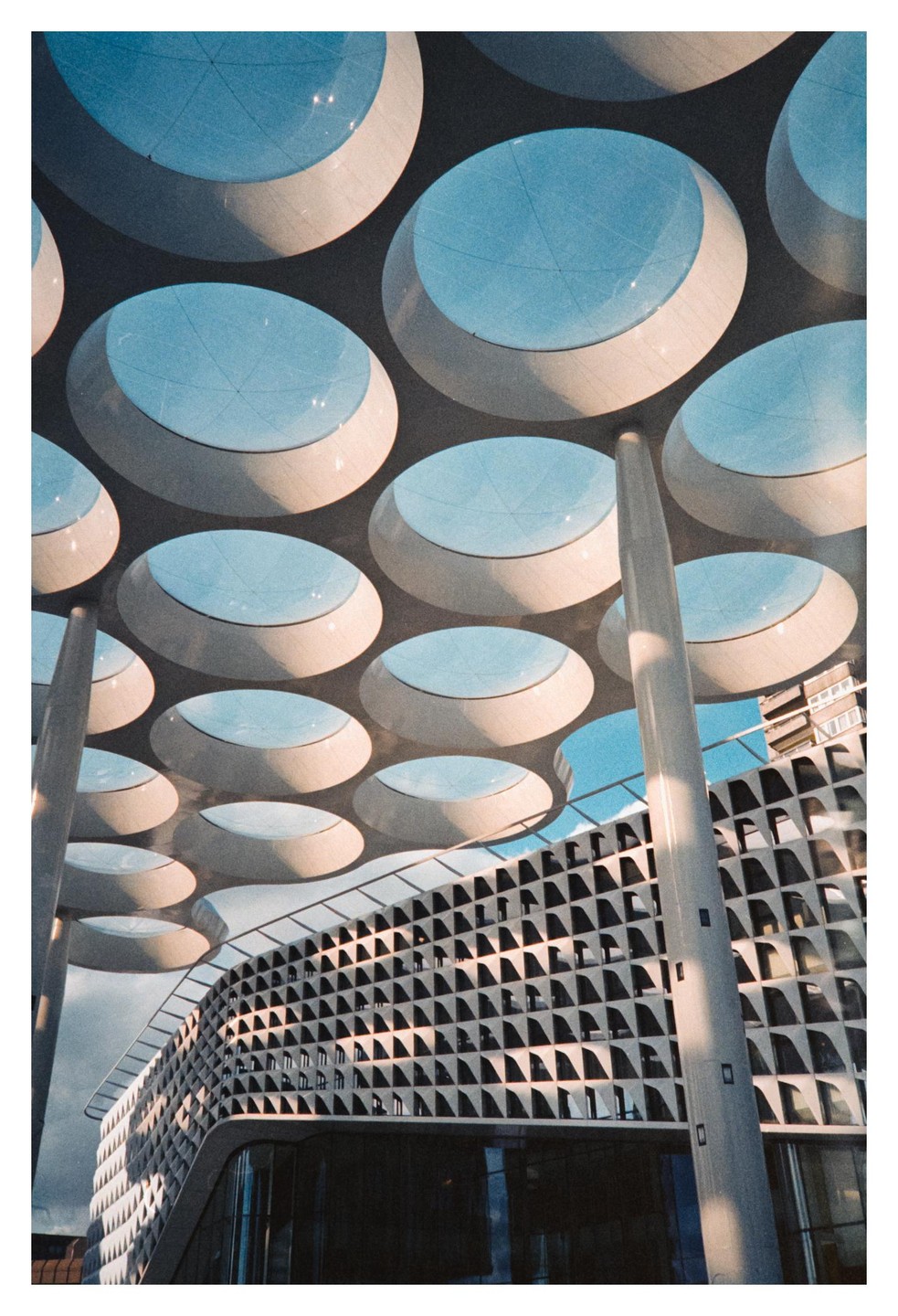 A modern building with a bubble canopy and a patterned facade is shown from a low angle.