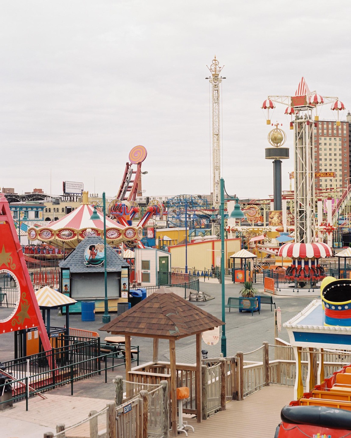 An empty amusement park with various rides and attractions under an overcast sky.