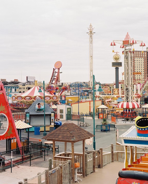 An empty amusement park with various rides and attractions under an overcast sky.