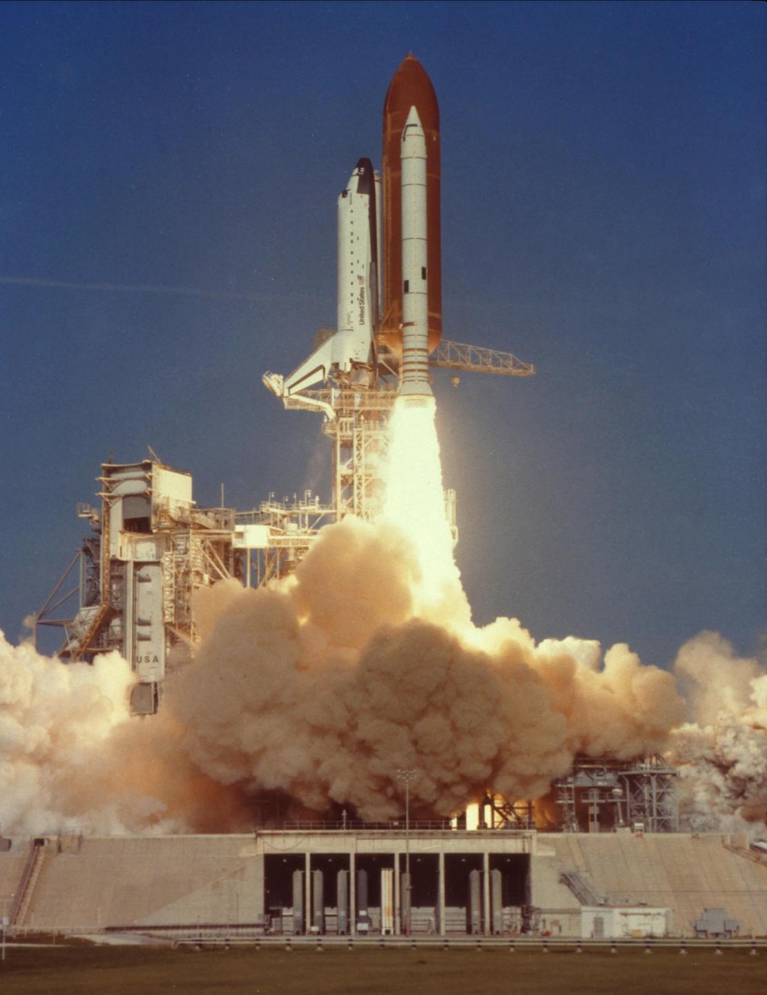 A space shuttle launches from a launchpad, surrounded by smoke and fire.