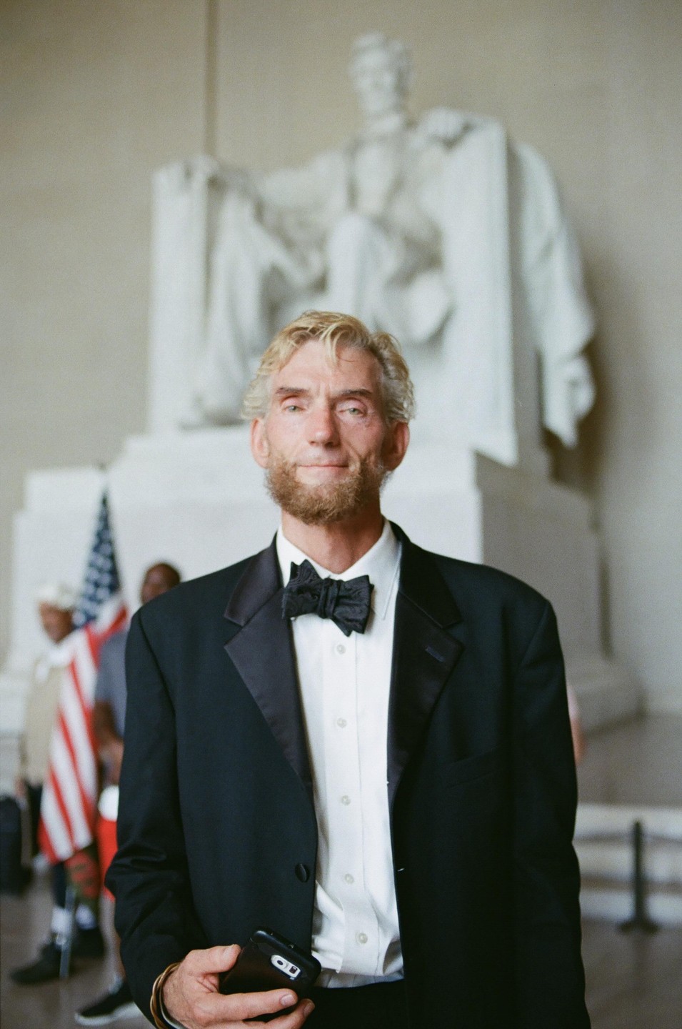 A man dressed as Abraham Lincoln stands in front of the Lincoln Memorial.