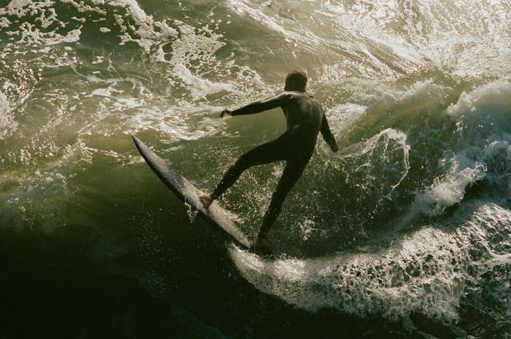 A surfer in a wetsuit rides a wave on a surfboard.