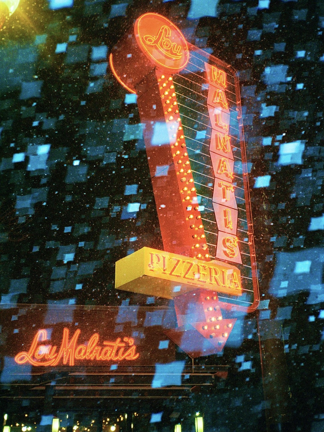 A neon sign for Lou Malnati's Pizzeria glows brightly against a dark, textured background.