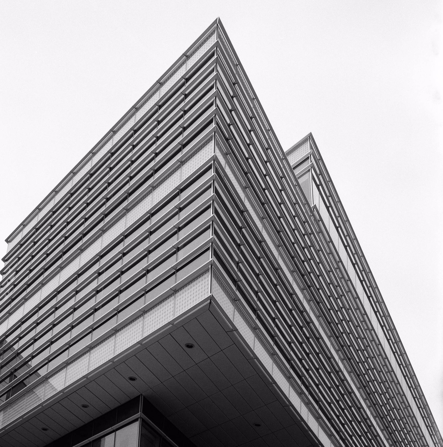 A modern building with many windows is photographed from a low angle.