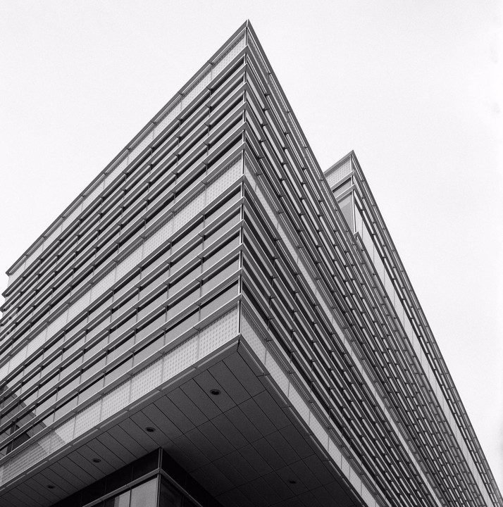 A modern building with many windows is photographed from a low angle.