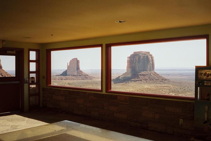 Two large rock formations are visible through the windows of a building with a yellow ceiling and stone wall.