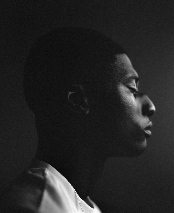 A man's profile is visible in a black and white portrait with strong shadow.