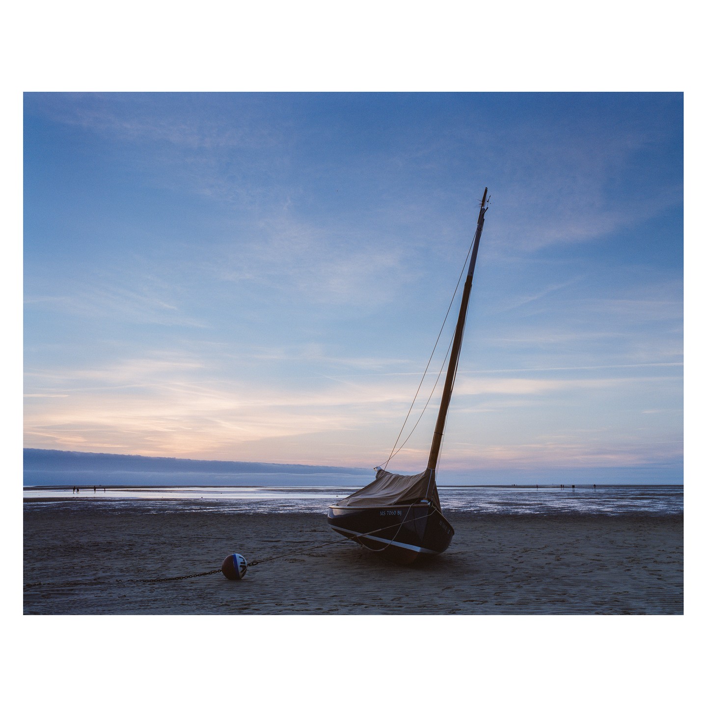 A small sailboat is beached on a sandy shore under a pastel sky at dusk.
