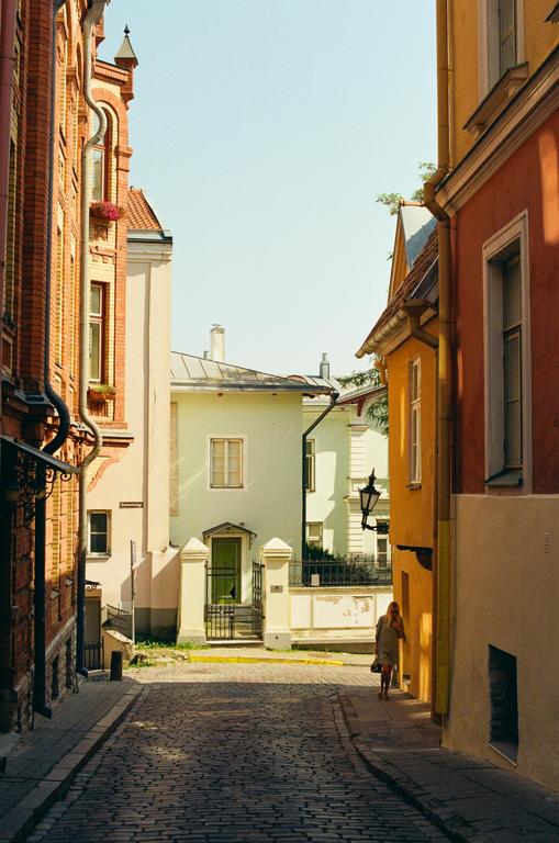 A woman walks down a cobblestone street lined with colorful buildings.