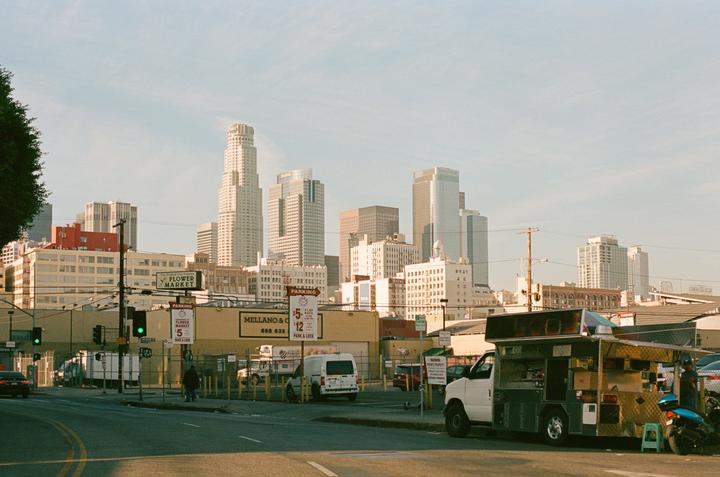 A food truck is parked on a street with tall buildings in the background.