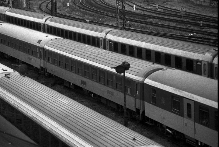 Three trains are parked on multiple tracks at a train station.