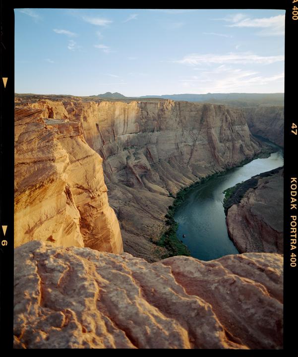 A river winds through a deep canyon with steep, rocky walls under a clear sky.