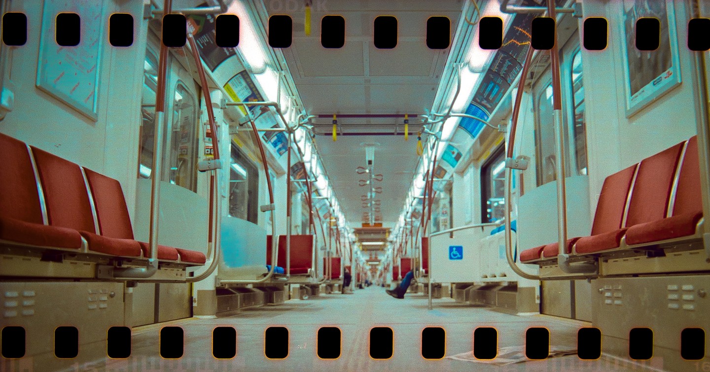 The interior of a subway car is empty except for one person's legs visible in the distance.