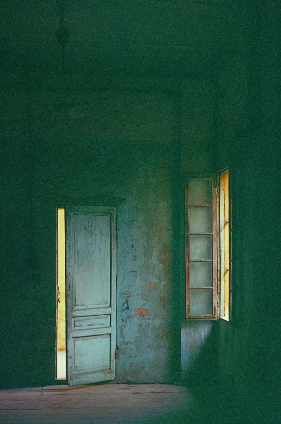 A door and a window are visible in a room with peeling paint.