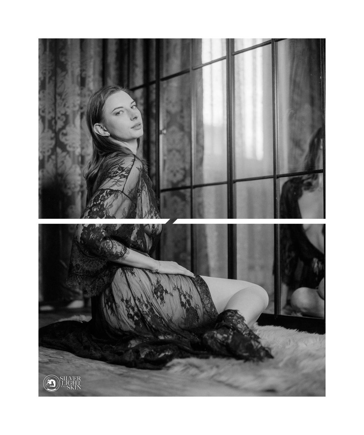 A woman in a lace robe sits on a rug in front of a window with a reflection.