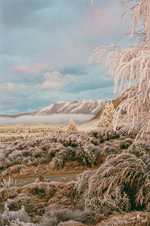 A frosty landscape with snow-capped mountains and a cloudy sky.