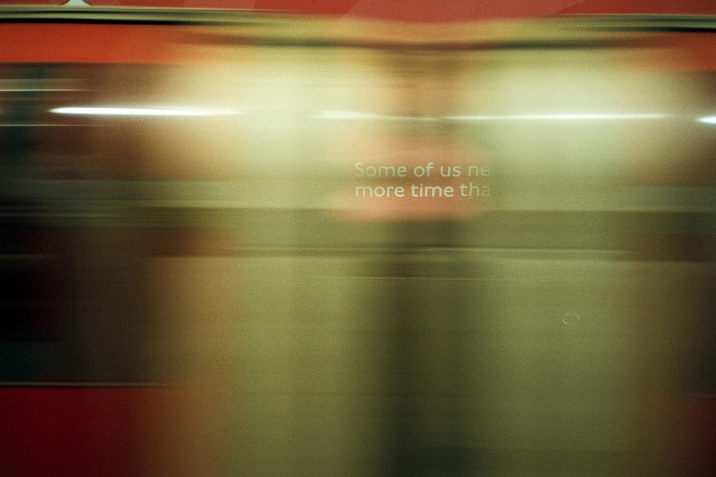 A blurry image shows a red and gold surface with white text that reads "Some of us need more time than."