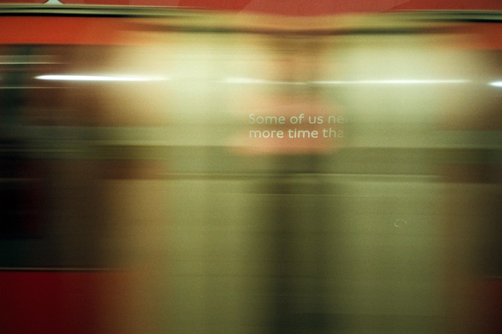 A blurry image shows a red and gold surface with white text that reads "Some of us need more time than."