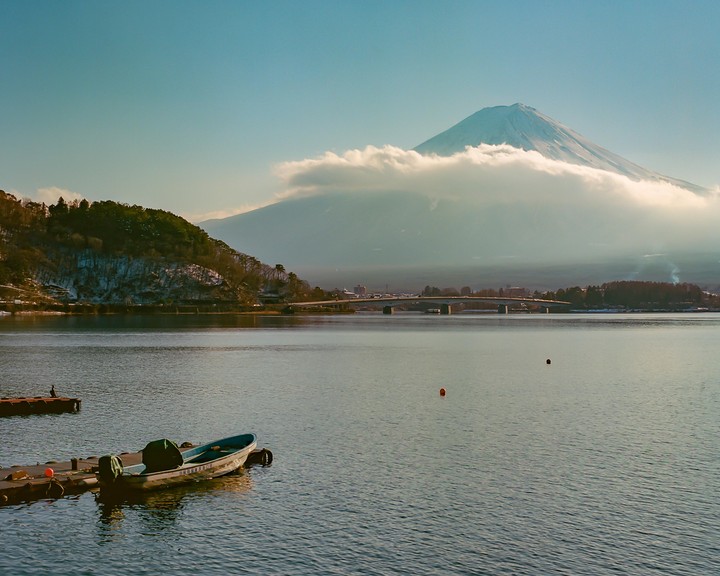 A boat is docked on a lake with a snow-capped mountain in the background.