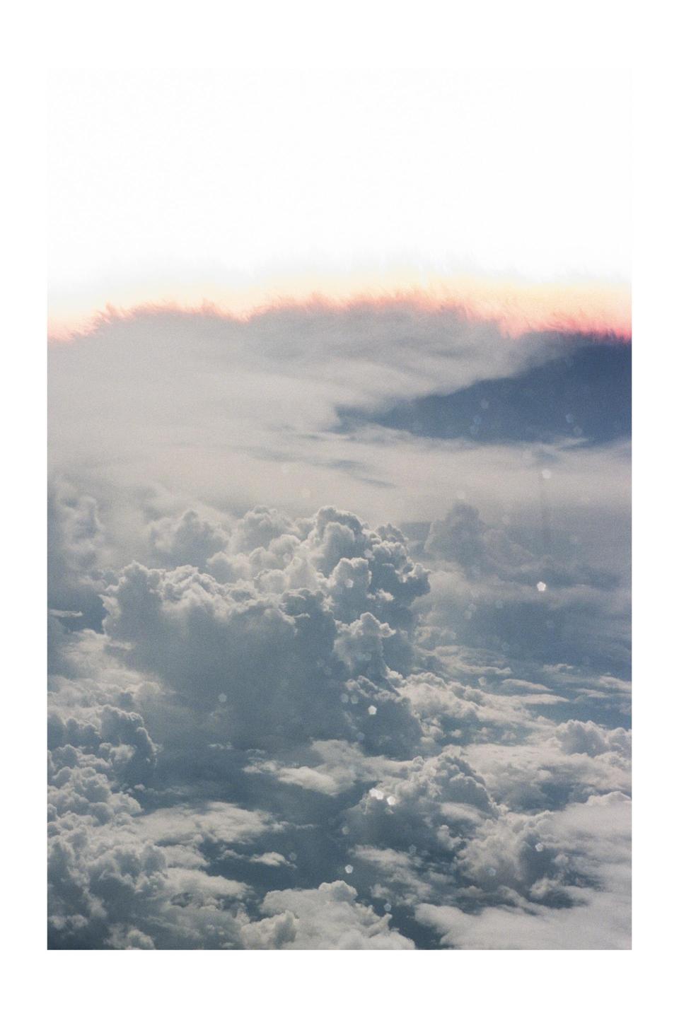 A view from above shows a vast expanse of clouds with a hint of pink light at the top.