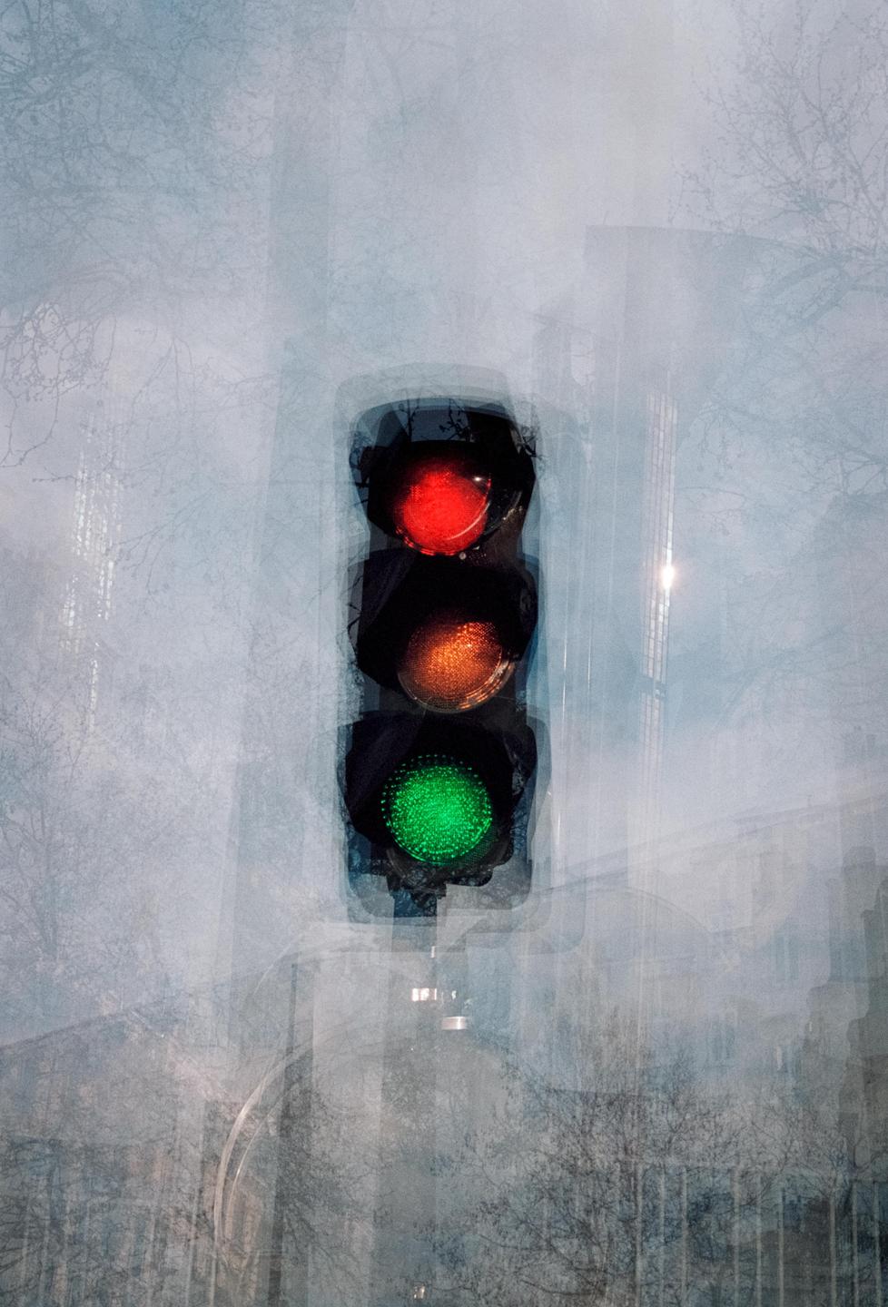 A traffic light with red, orange, and green lights is visible through a hazy, layered effect.
