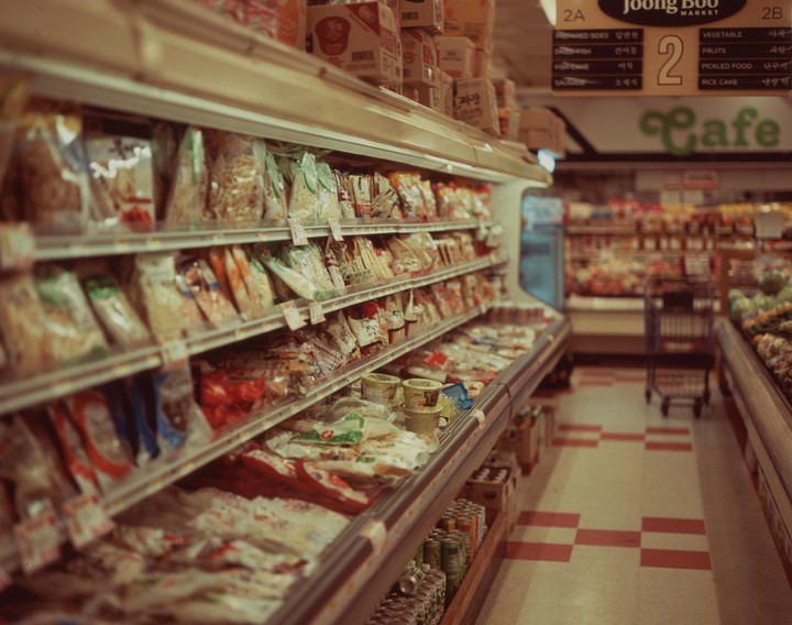 A grocery store aisle is filled with packaged food items on shelves and in refrigerated displays.