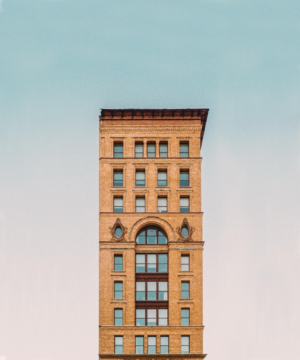 A tall brick building with many windows stands against a clear sky.