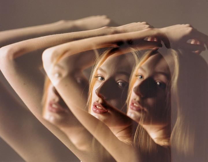A woman's face and arms are visible through a multiple exposure effect.