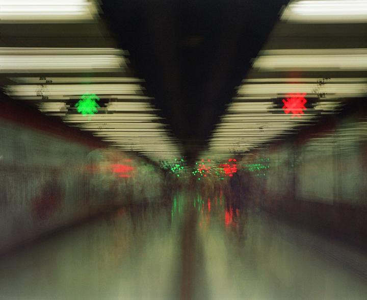 A blurry image shows a subway tunnel with green and red lights.