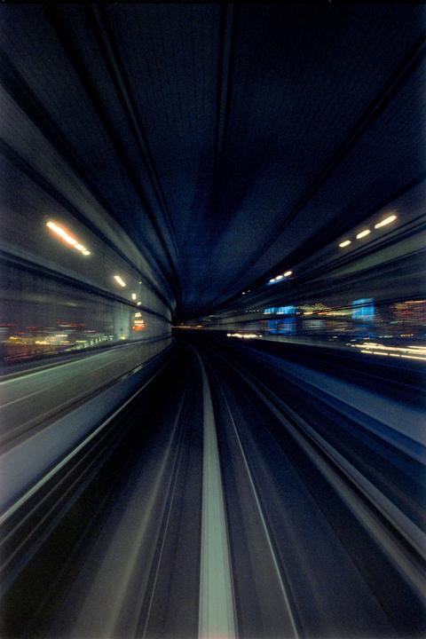 A long exposure shot from the front of a train shows the tracks and tunnel walls blurring into streaks of light and color.
